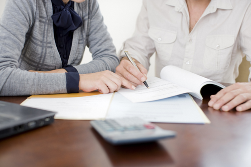 Empresaria firmando papeleo con un gerente de relaciones, que ayuda a aclarar las pautas de préstamo de la SBA